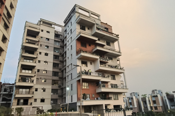Side view of Infinity Heights featuring tiered balconies and a sunset glow on the horizon.
