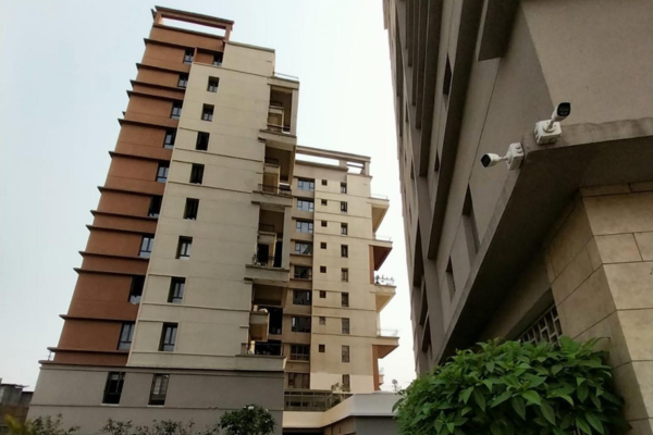 Ground-level perspective of Infinity Heights with adjacent building and security cameras.