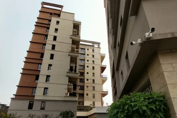 Ground-level perspective of Infinity Heights with adjacent building and security cameras.
