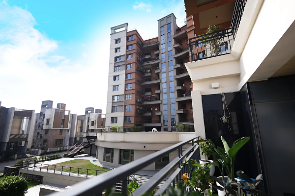 View of the modern building exterior showcasing Luxury Apartments at Infinity Heights, possibly in Guwahati, with an outdoor common area visible from a balcony.