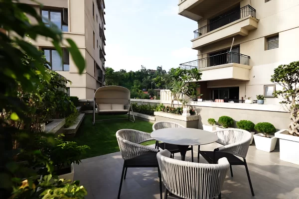 A cozy outdoor sitting area and swing on a terrace, highlighting the relaxing amenities of the Luxury Apartments at Infinity Heights in Guwahati.