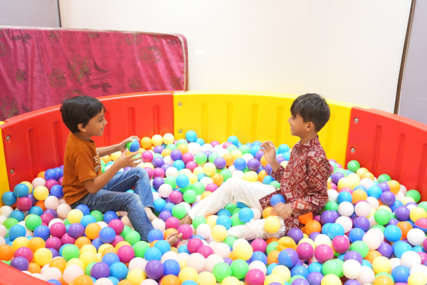 Two young boys laugh and play in a colorful ball pit at the Infinity Heights 'Parivaar Ke Sitaare' celebration. This shows the dedicated children's play area, a key amenity for families looking to buy apartment in guwahati.