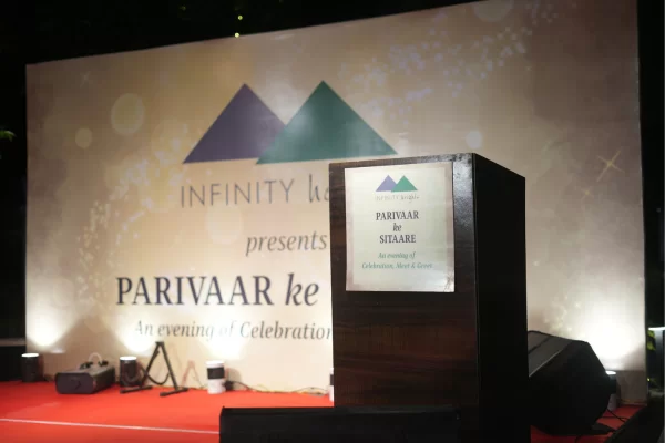 This image shows the main stage backdrop for the "Parivaar ke Sitaare" event presented by Infinity Heights. The podium is set for an evening of celebration and meet & greet.