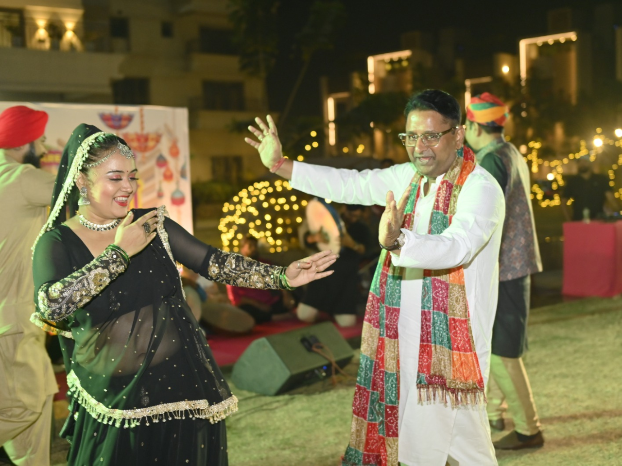 A resident and a traditional folk dancer joyfully dancing together at the Infinity Heights Holi celebration in Guwahati.