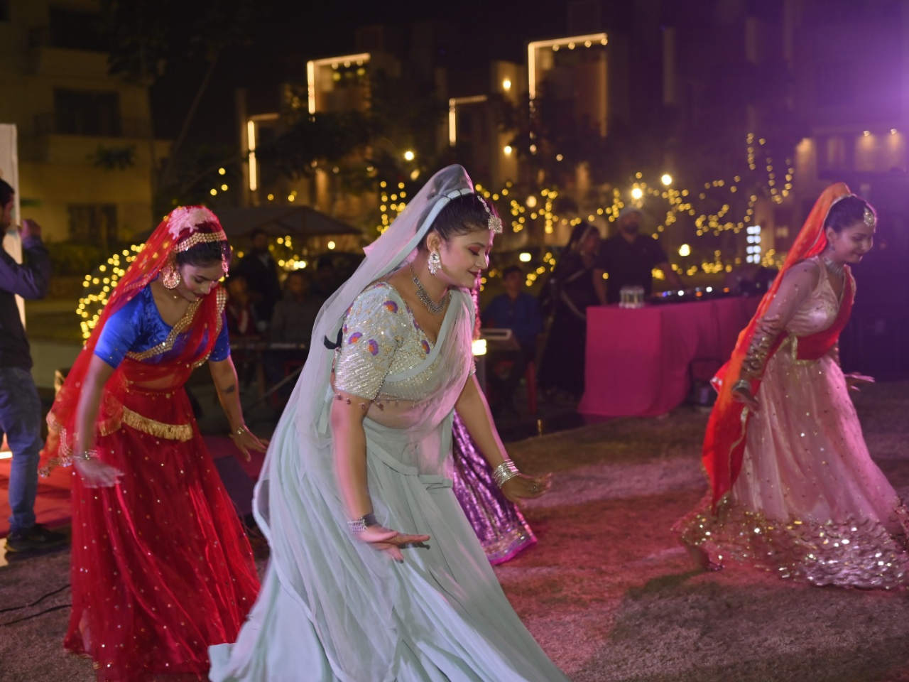 Traditional folk dancers performing gracefully in colorful ghagras during the evening Holi festivities at an apartment in Guwahati.