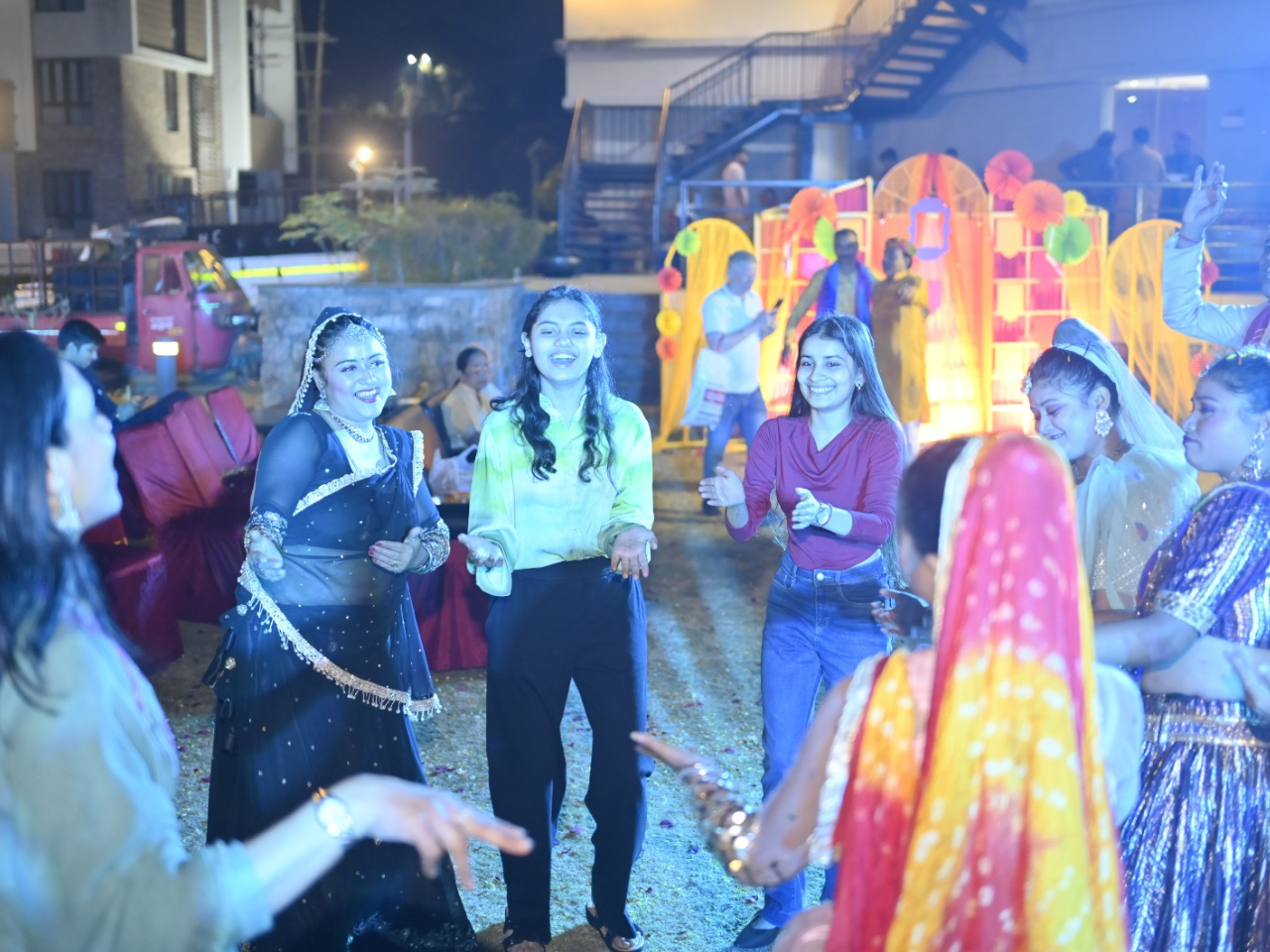 Residents and dancers sharing joyful moments and dancing together at the Infinity Heights Holi event.