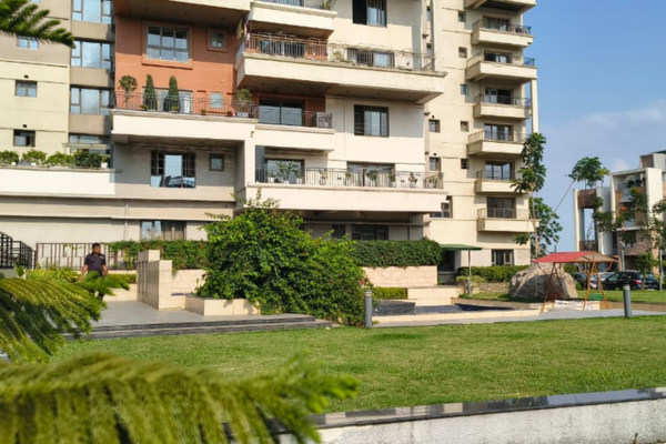 Exterior view of a modern multi-storey apartment building with private balconies overlooking a manicured lawn.