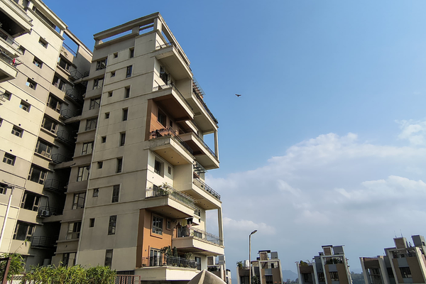 Exterior view of Infinity Heights' modern luxury high-rise apartment building against a blue sky.