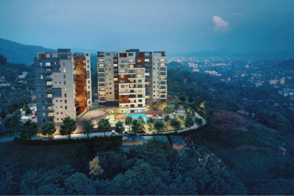 Aerial view of Infinity Heights luxury hilltop residential towers in Kalapahar, Guwahati, surrounded by lush green hills at twilight.