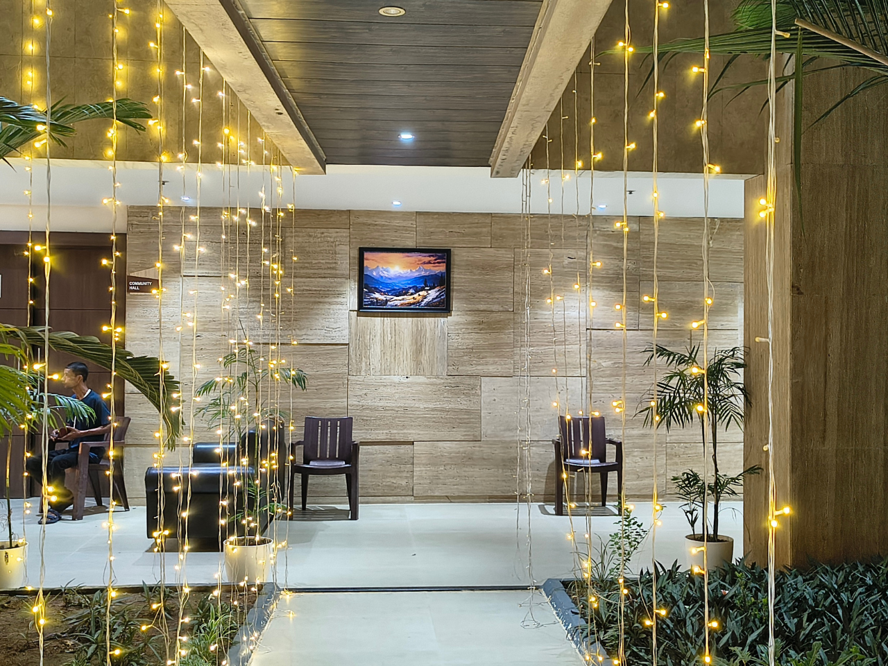 A modern indoor lobby area illuminated with hanging fairy light strings and palm plants.