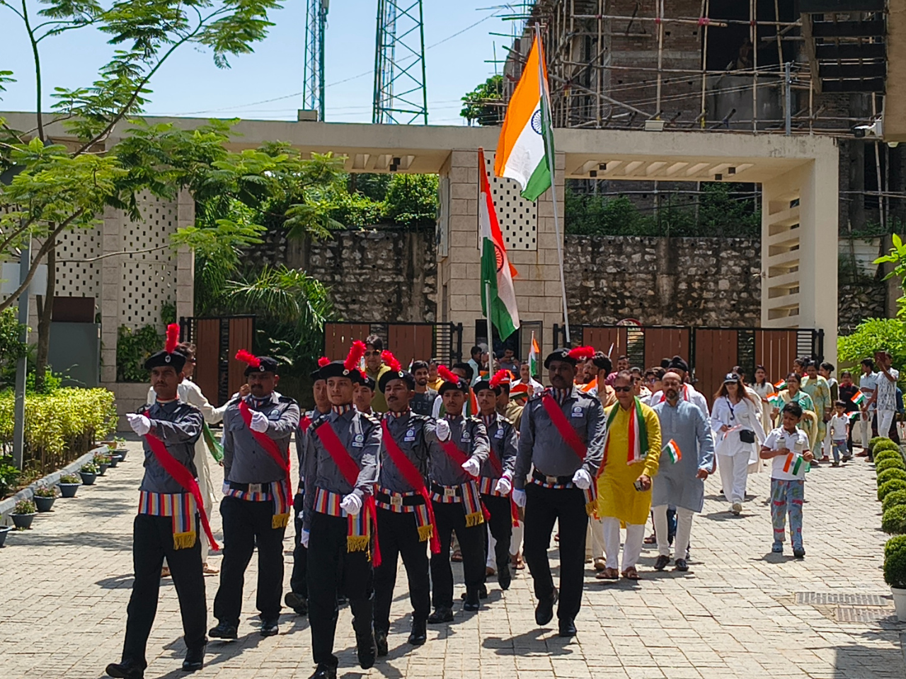Security guards marching in a parade followed by residents and children carrying Indian flags at Infinity Heights.